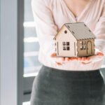 Mulher executiva segurando uma casinha de madeira